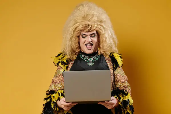 stock image A drag queen in fabulous attire smiles while using a laptop.