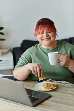 A woman enjoys a coffee break at home, savoring a croissant and a moment of peace. clipart