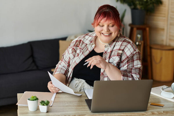 A woman sits at a desk, reviewing paperwork while smiling.
