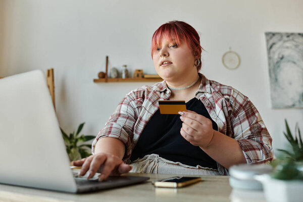 Женщина с розовыми волосами использует свой ноутбук и кредитную карту, чтобы сделать покупку.