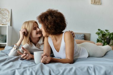 Çok kültürlü bir lezbiyen çift yatakta dinleniyor ve sıcak bir anı paylaşıyor..