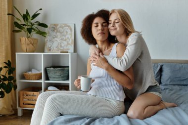 Sevgi dolu bir lezbiyen çift, evlerinde bir anlık yakınlık ve rahatlığın tadını çıkararak yatakta sarılır..