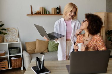 İki kadın evden bir projede birlikte çalışıyor, gülümsüyor ve fikirleri paylaşıyorlar..