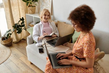 Bir çift, rahat oturma odalarındaki dizüstü bilgisayarlarda çalışır. Bir gülücük ve bir anlık bir bağ paylaşırlar..