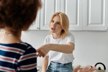 Two women argue in a kitchen, one gesturing while the other looks away, showcasing tension and misunderstanding in their relationship clipart