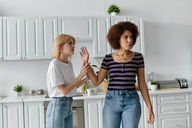 A lesbian couple argues in a kitchen, their faces etched with displeasure. clipart