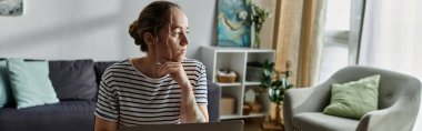 A woman with vitiligo reflects thoughtfully while seated in a stylish room. clipart