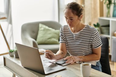 A young woman with vitiligo engages with her laptop in a sunlit cafe. clipart