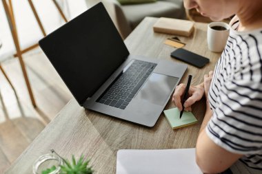 A woman with vitiligo writes notes while surrounded by a cozy workspace. clipart