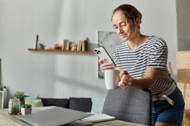 Vitiligo 'su olan bir kadın akıllı telefonuyla uğraşırken kahvesini yudumluyor..