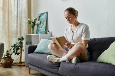 Vitiligo 'su olan bir kadın rahatlar ve rahat bir koltukta kitap okur..