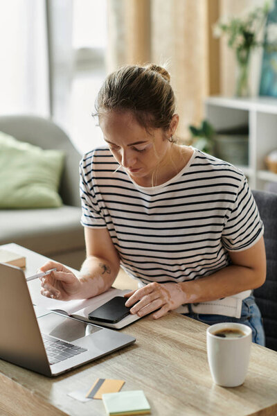 Женщина с витилиго интенсивно работает за своим ноутбуком в теплом, уютном месте.