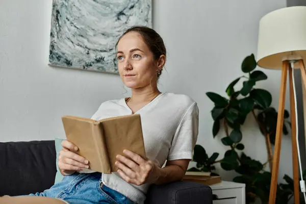 stock image A young woman with vitiligo enjoys reading, surrounded by a warm, inviting atmosphere.