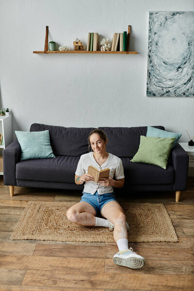 Женщина с витилиго сидит на полу наслаждаясь книгой в спокойном месте.