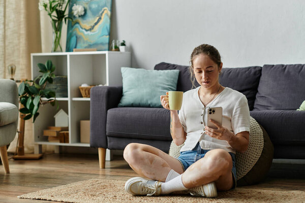 A woman with vitiligo relaxes with a cup, engaged in her phone in a cozy setting.