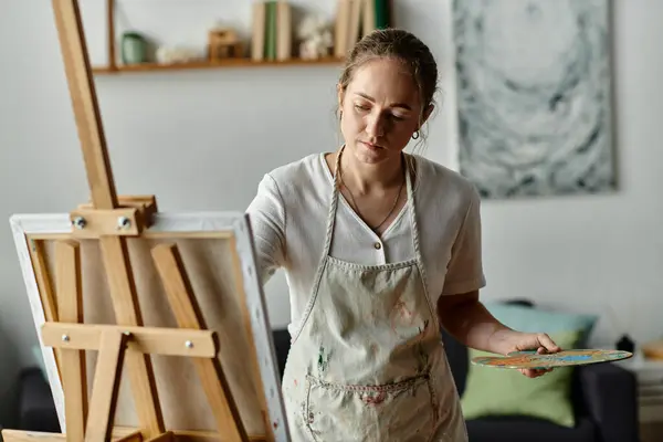 stock image A talented woman with vitiligo paints thoughtfully in her cozy studio.