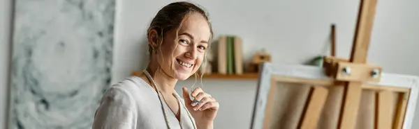 stock image A woman with vitiligo smiles warmly while painting in her artistic workspace.