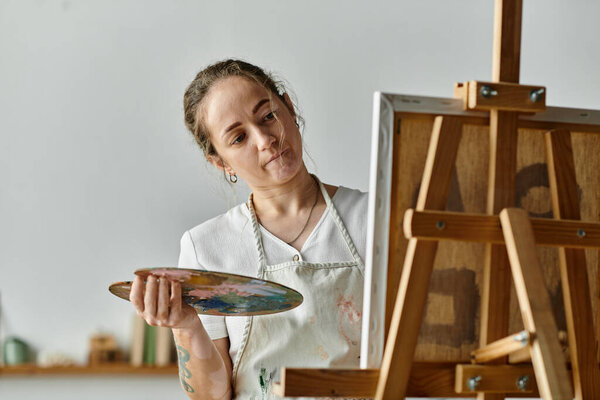 A young artist thoughtfully blends colors on her palette while painting.