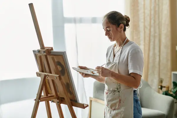 stock image A young woman with vitiligo passionately paints in her cozy studio.