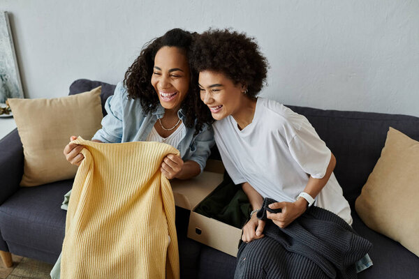 Two partners joyfully transform their clothes on a cozy sofa.