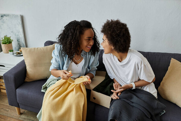 Пара радостно поднимает свою одежду, делясь улыбками в комфортной обстановке.