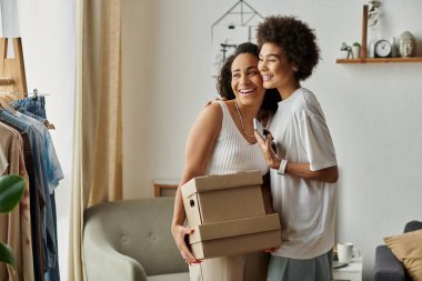 Couple joyfully transforming their wardrobe with upcycled clothing, box in hands. clipart