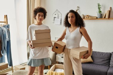 Couple engages in upcycling clothing while organizing their personal space, boxes in hands. clipart