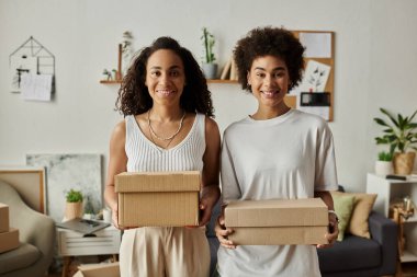 Couple joyfully reimagines clothing while holding up boxes. clipart