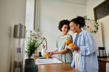 A couple enjoys preparing fresh fruit together in their sunny kitchen. clipart