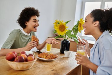 Güzel bir çift, güneşli bir mutfakta kahkaha ve kahvaltıyı paylaşır..