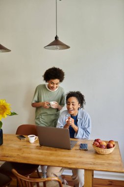 Gülen çift evde dizüstü bilgisayarla çalışırken keyifli bir anın tadını çıkarıyor..