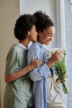 A couple shares a tender moment while embracing and admiring flowers. clipart