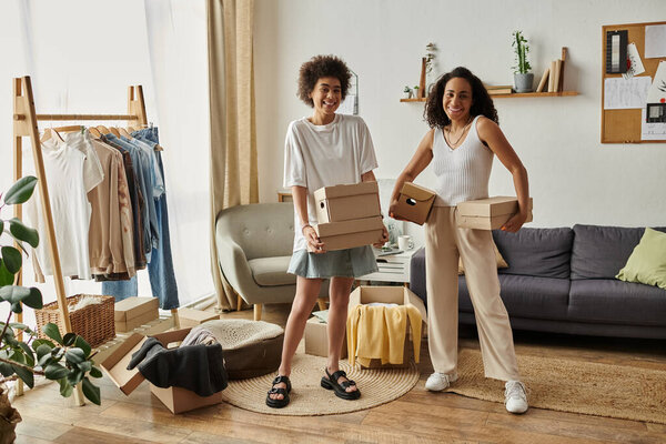 Пара счастливо превращает старую одежду в стильные вещи в их ярком доме, коробки в руках.