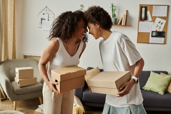 Пара делится игривым моментом во время апвеллинга одежды в креативной гостиной, держа коробки.