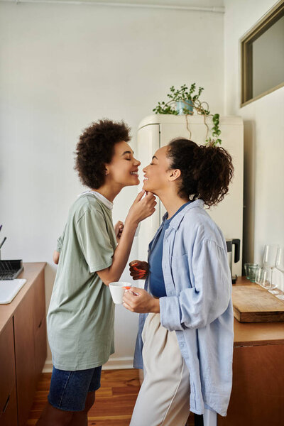 Две женщины разделяют сладкий момент, наслаждаясь друг с другом компанией на своей кухне.