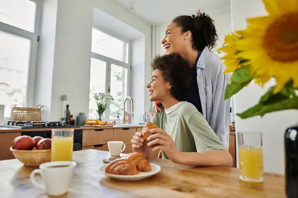 stock image Two women share laughter and breakfast, surrounded by warmth and sunlight.