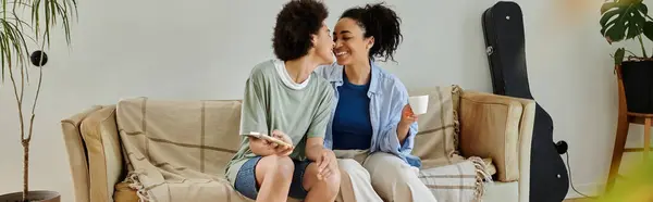 stock image Two women enjoy each other's company while smiling on the couch.