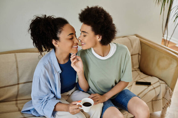 Две женщины разделяют нежный момент, наслаждаясь кофе дома.