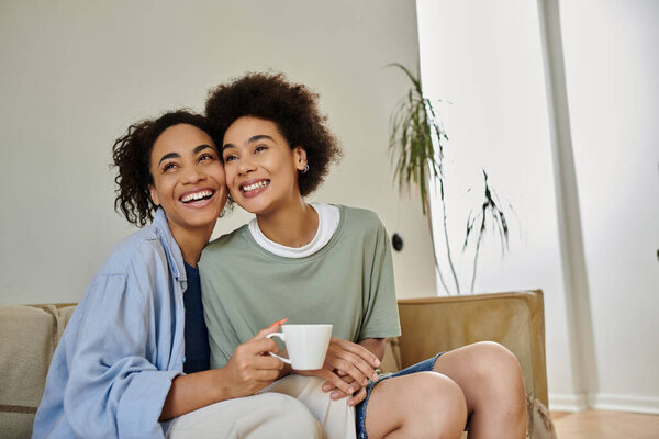 Любящая лесбийская пара делится смехом и радостью, расслабляясь в помещении.