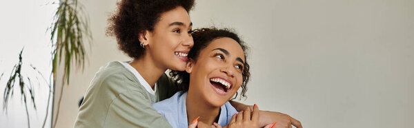 Two women share joyful laughter and affectionate moments at home.
