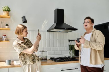 İki arkadaş sıcacık bir anın tadını çıkarır, biri şık bir mutfakta fotoğraf çeker..