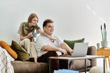 İki arkadaş evde dizüstü bilgisayar üzerinde çalışırken neşe ve yaratıcılığı paylaşıyor.