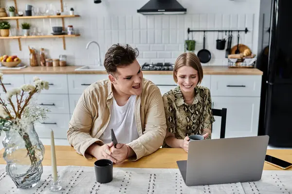 stock image A joyful moment shared over a laptop in a modern kitchen.