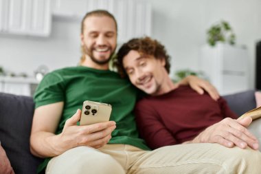 İki ortak, telefonlarını kanepede kullanırken neşe ve kahkahayı paylaşır..