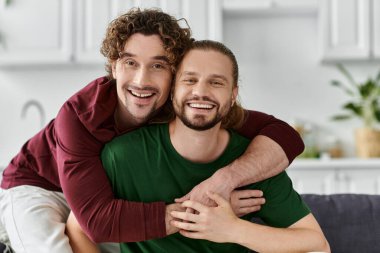 Neşeli bir eşcinsel çift sıcak evlerinde sevgi dolu bir kucaklaşmayı paylaşıyor..