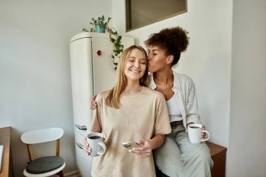 A happy couple shares a tender moment while sipping coffee at home.