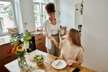 İki ortak, güneşli mutfaklarında kahvaltı ederken keyifli bir anı paylaşıyor..
