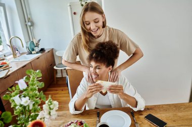 İki eş, evde yemeğin tadını çıkarırken neşeli bir anı paylaşıyor..
