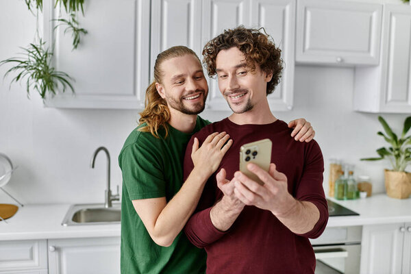 A happy gay couple enjoys a tender moment while viewing a phone together.