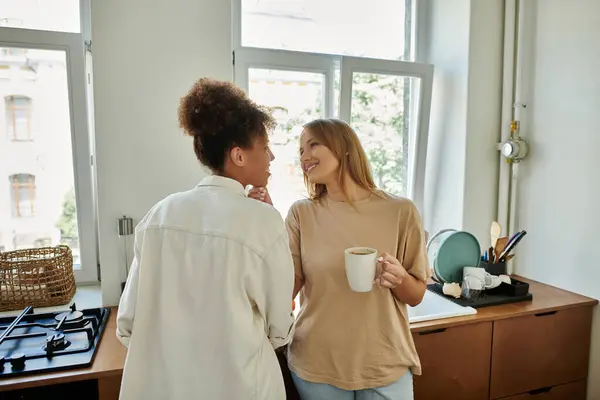 stock image Two partners share a joyful moment while sipping coffee in their cozy kitchen.